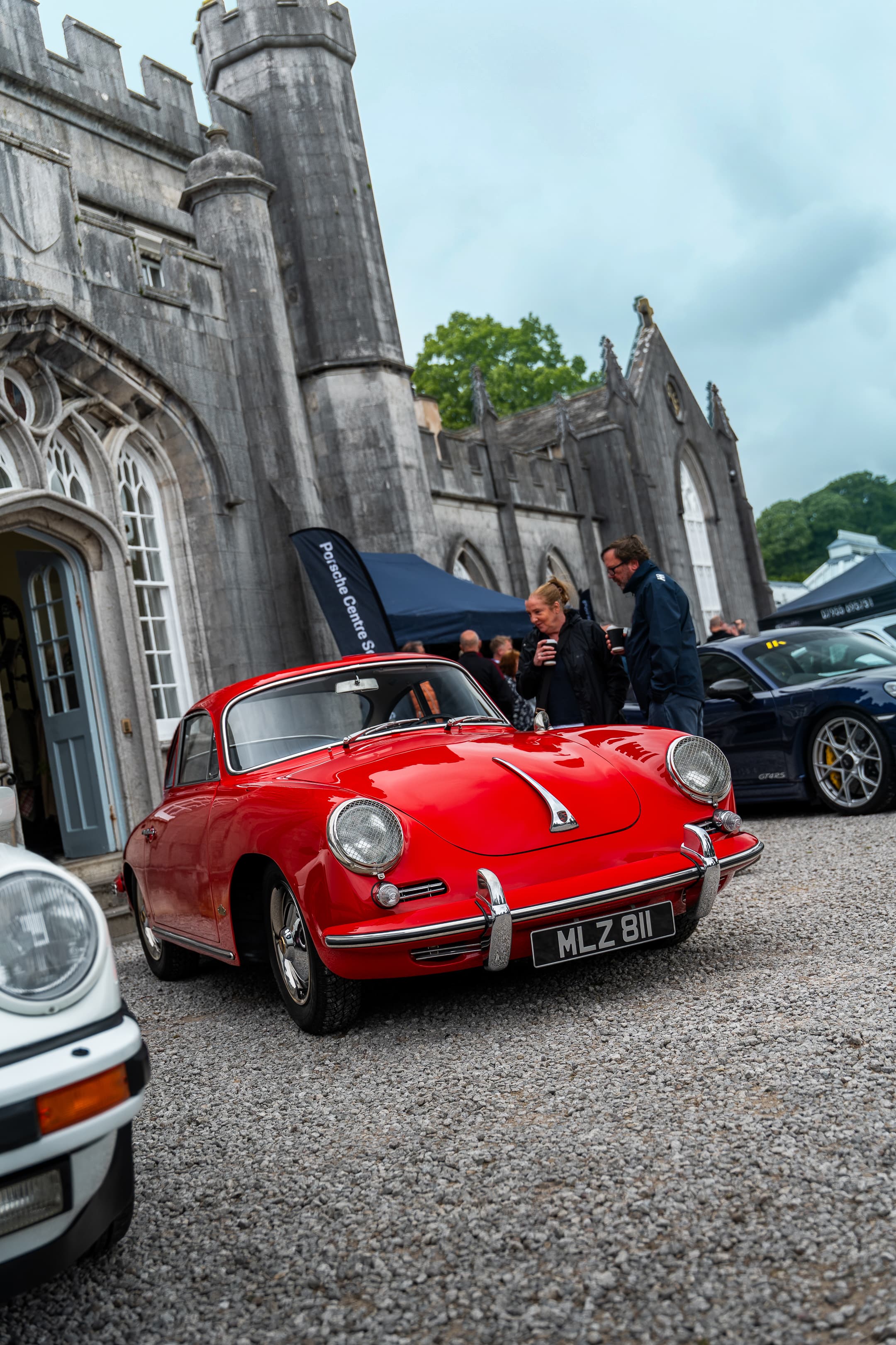 A classic red Porsche 356 parked in front of Leighton Hall at Renntag