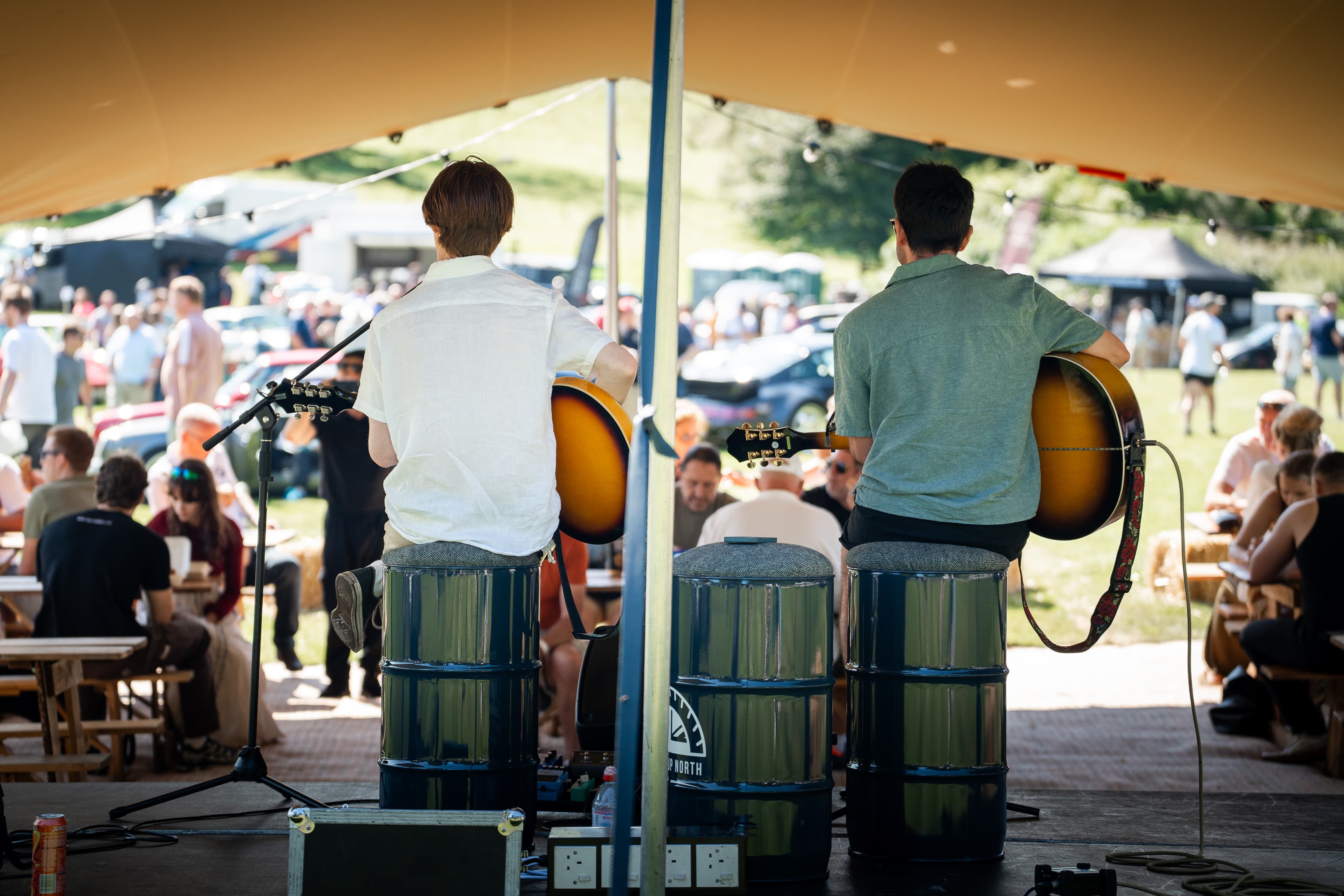 Live music under a marquee with visitors seated around, at Renntag