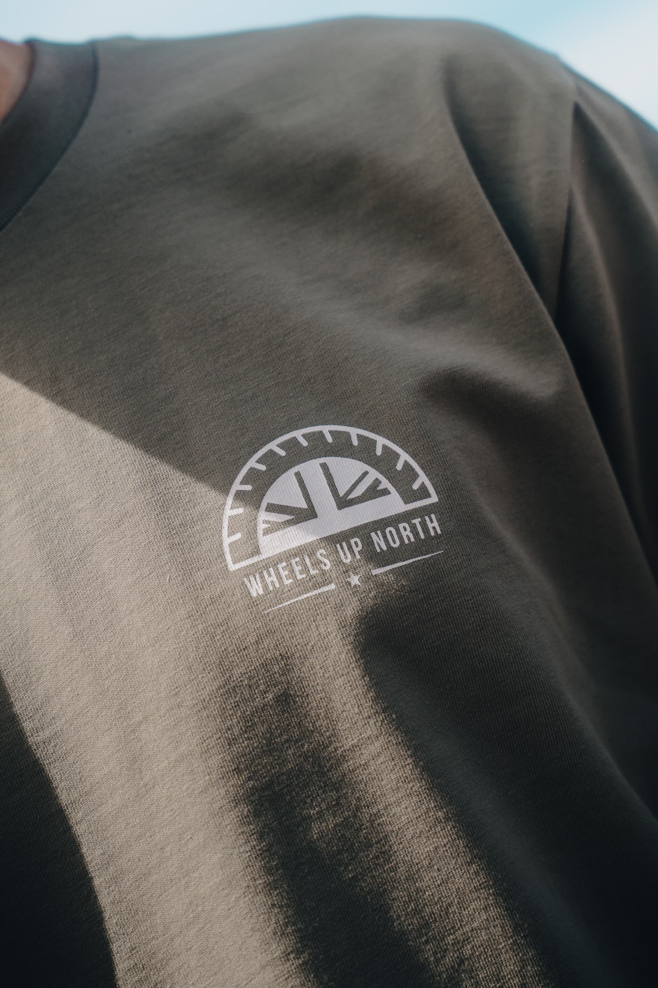 WUN Club T-Shirt - Green - close-up of the wheels up north chest logo on the green club t-shirt